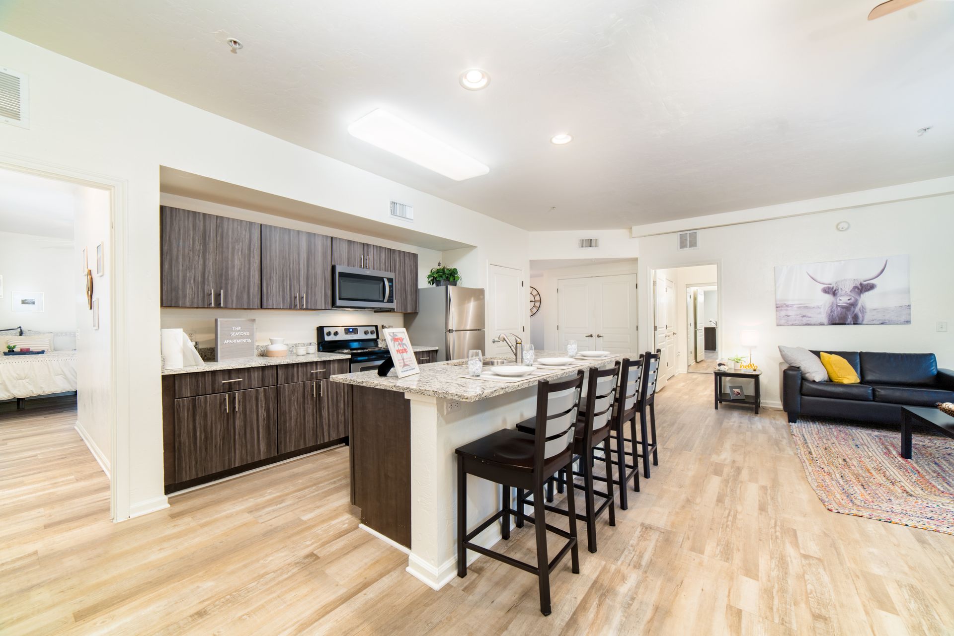 A four-seat island, fully furnished living room, and a peek into a private bedroom at The Seasons.