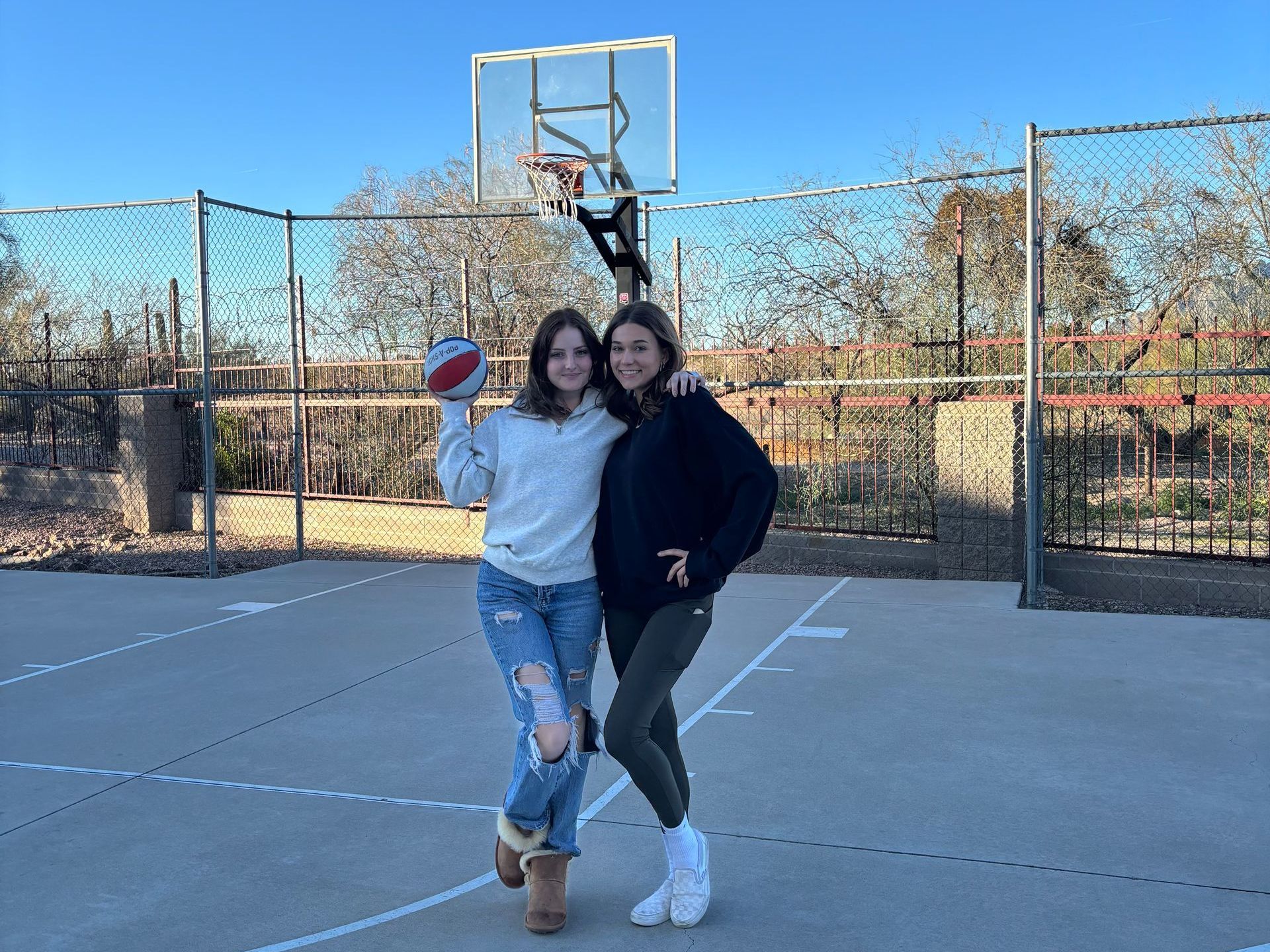 Two female residents in cozy winter outfits pose with a basketball.