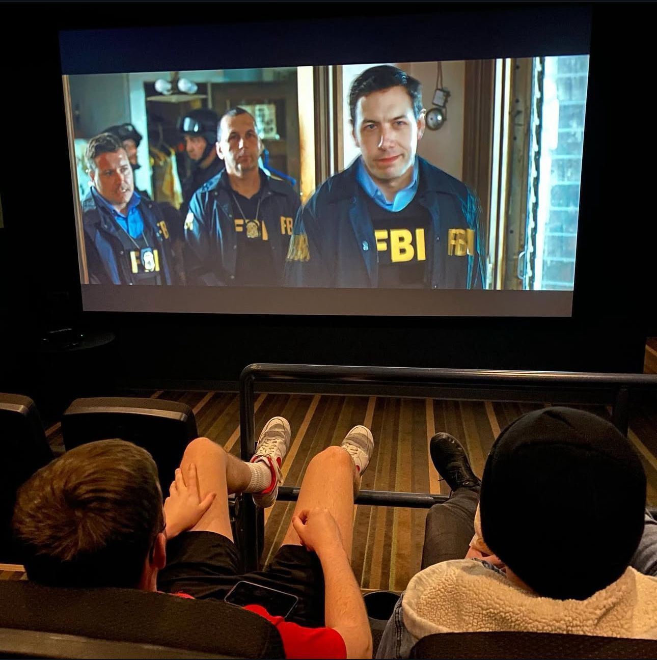 Male residents watching a movie on The Seasons' big screen on-site theater.