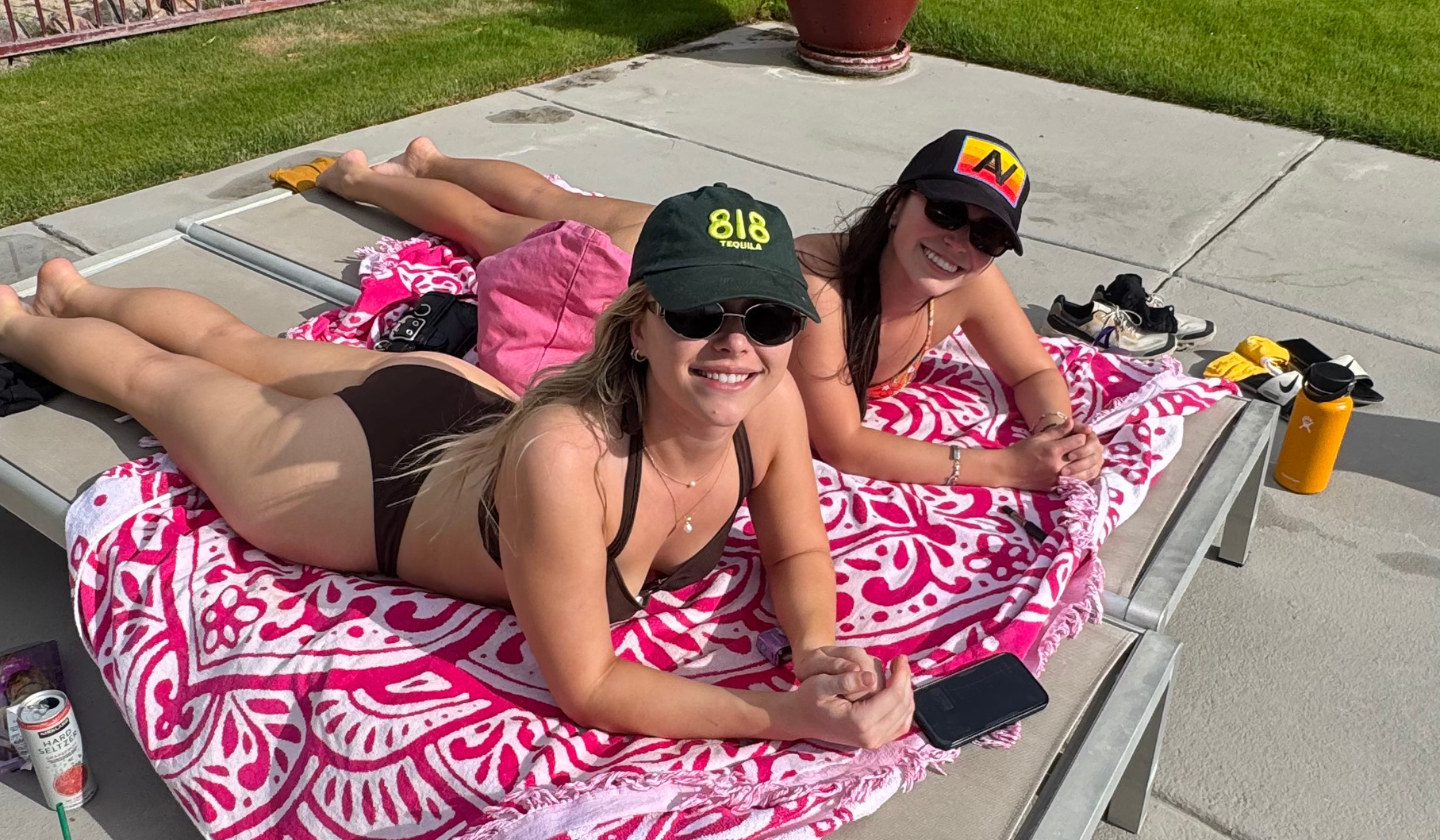 Two residents sunbathing in pool chairs by the resort-style pool at The Seasons Tucson.