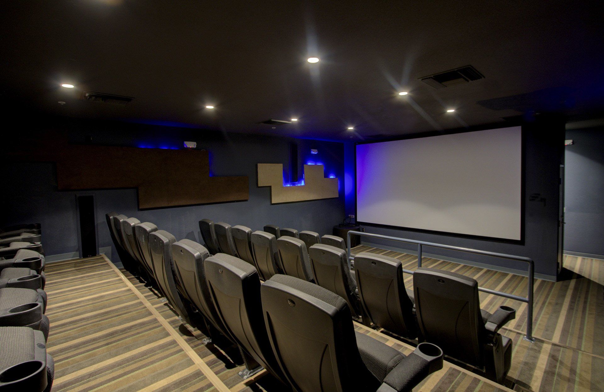 A private movie theater with three rows of recliners and a wide screen projector.