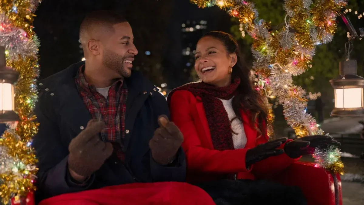 Christina Milan and Devale Ellis are smiling and riding in a sleigh at night in the movie Meet Me Next Christmas.