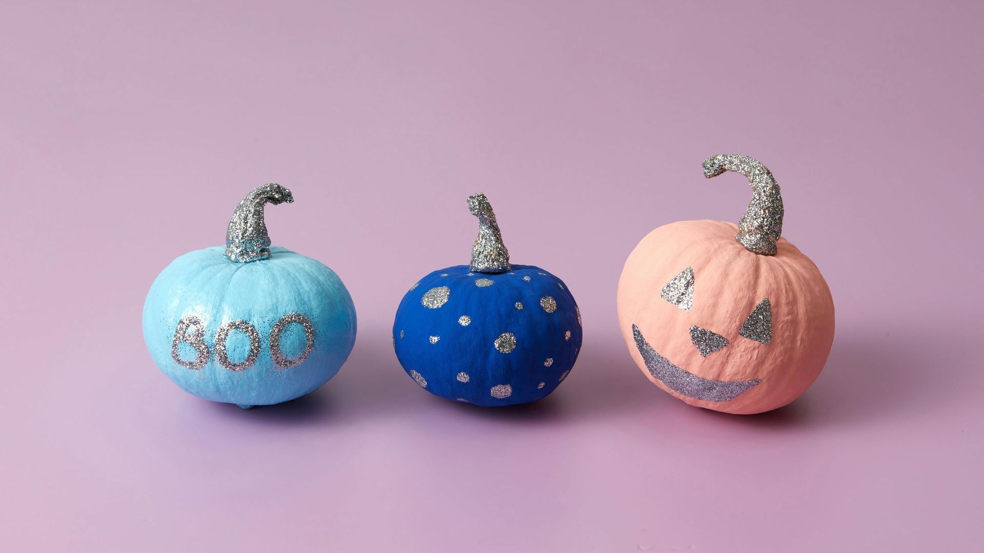 Three DIY painted pumpkins for Halloween decor.