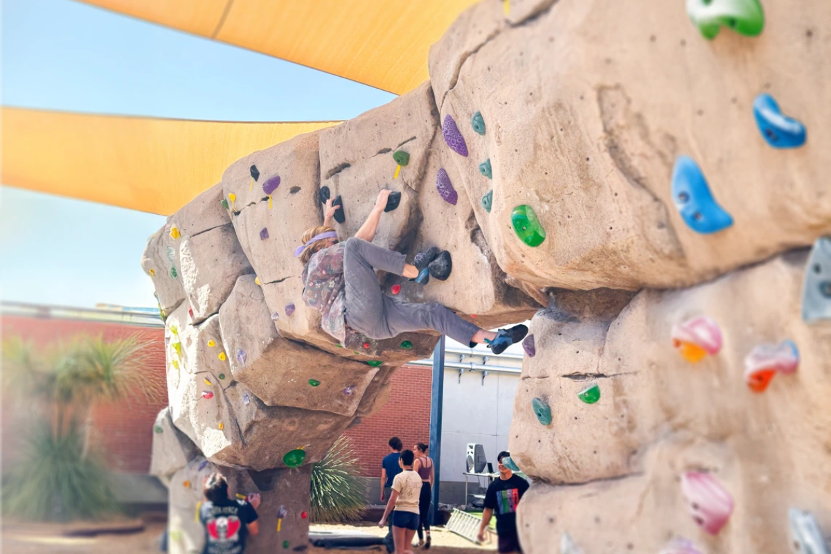 A climber tackles an outdoor bouldering wall at the rec center.