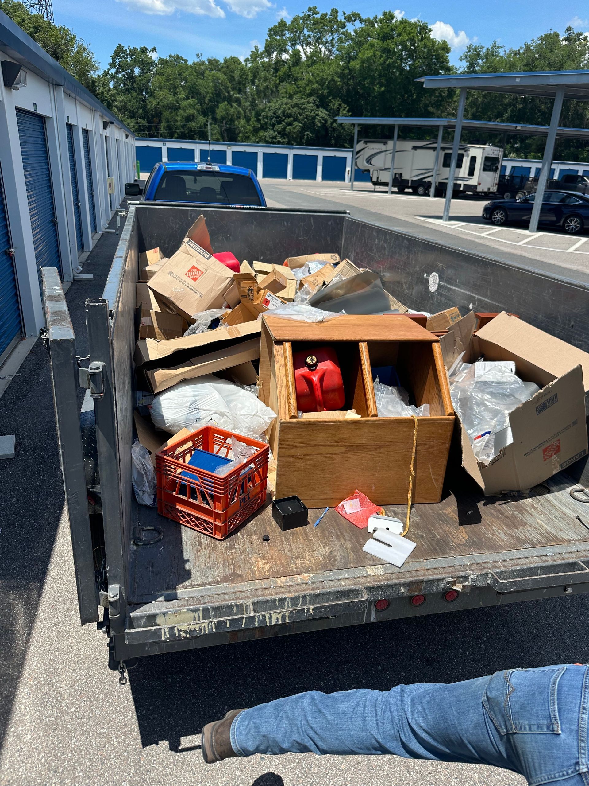 Pickup truck bed filled with assorted boxes and items in a storage unit parking lot.