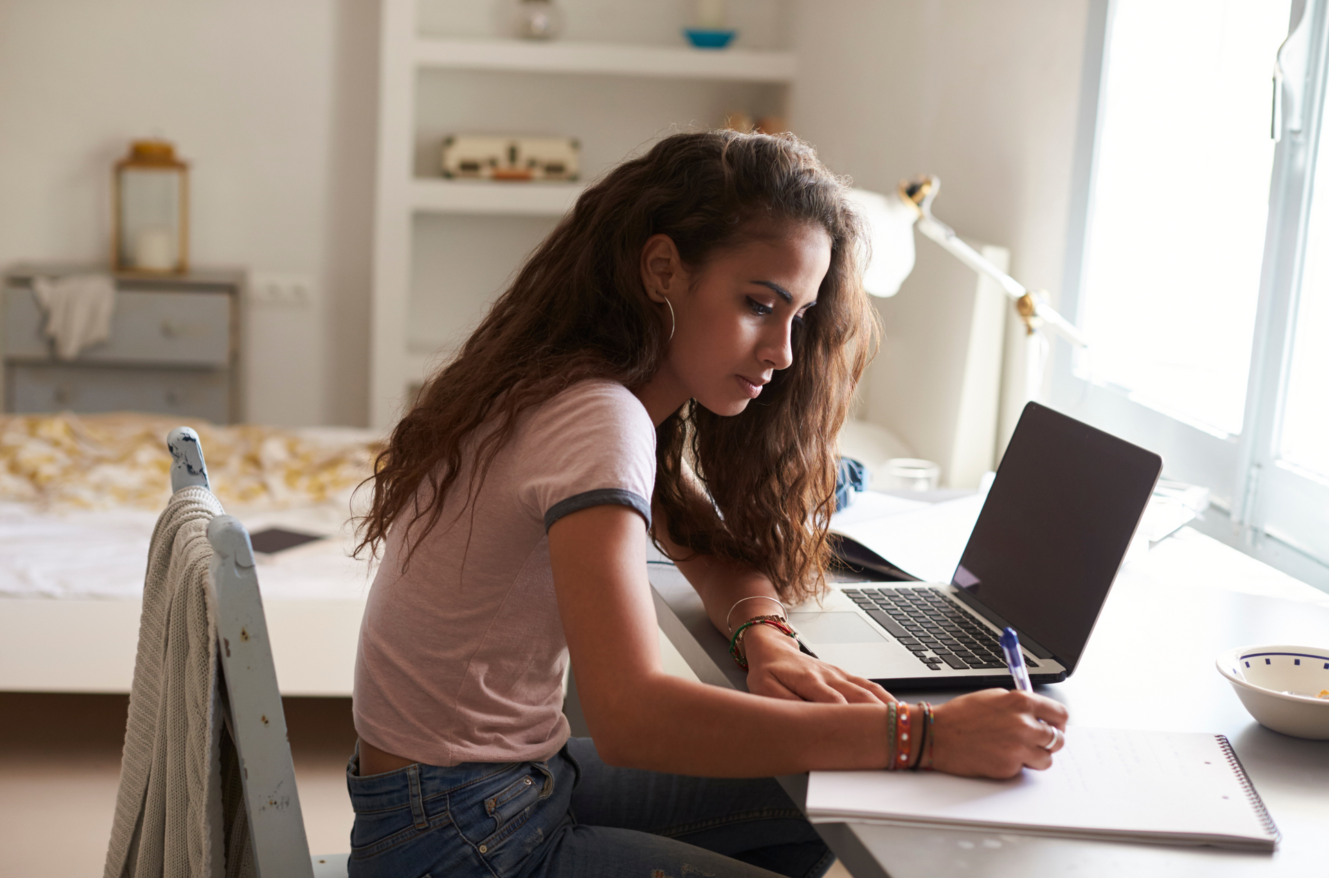 Een jonge vrouw zit aan een bureau en gebruikt een laptopcomputer.