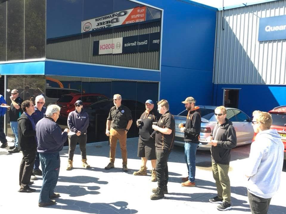 A Group Of Men Are Standing Outside Of A Car Dealership — Queanbeyan Diesel Service In Queanbeyan, East NSW