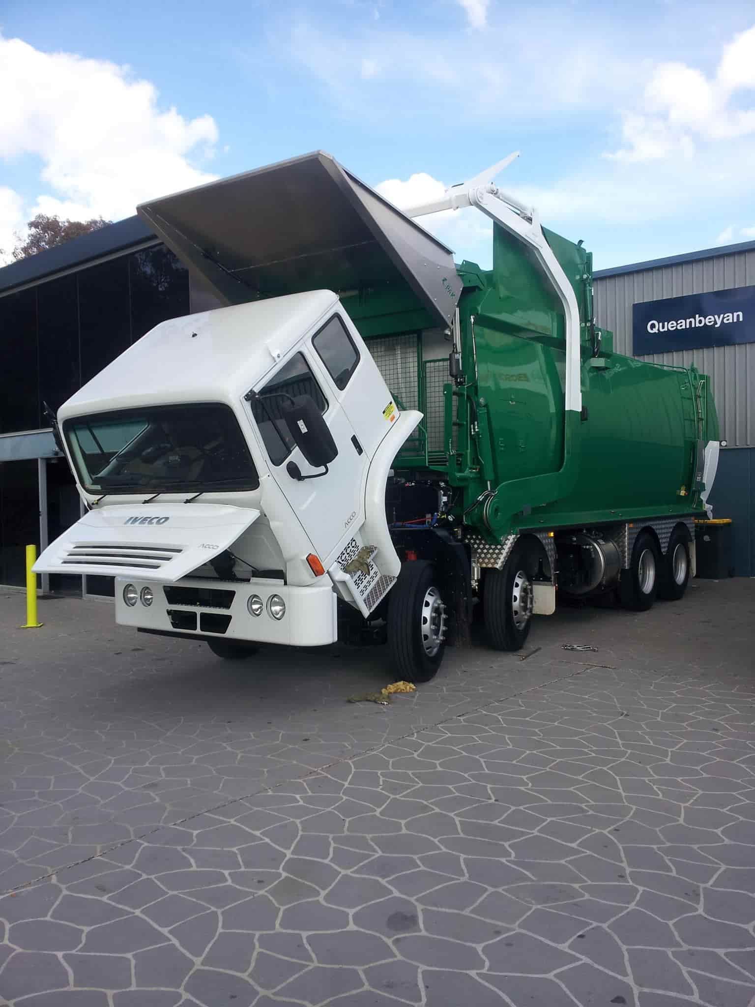 A Green Garbage Truck With Its Hood Up Is Parked In Front Of A Building — Queanbeyan Diesel Service In Queanbeyan, East NSW