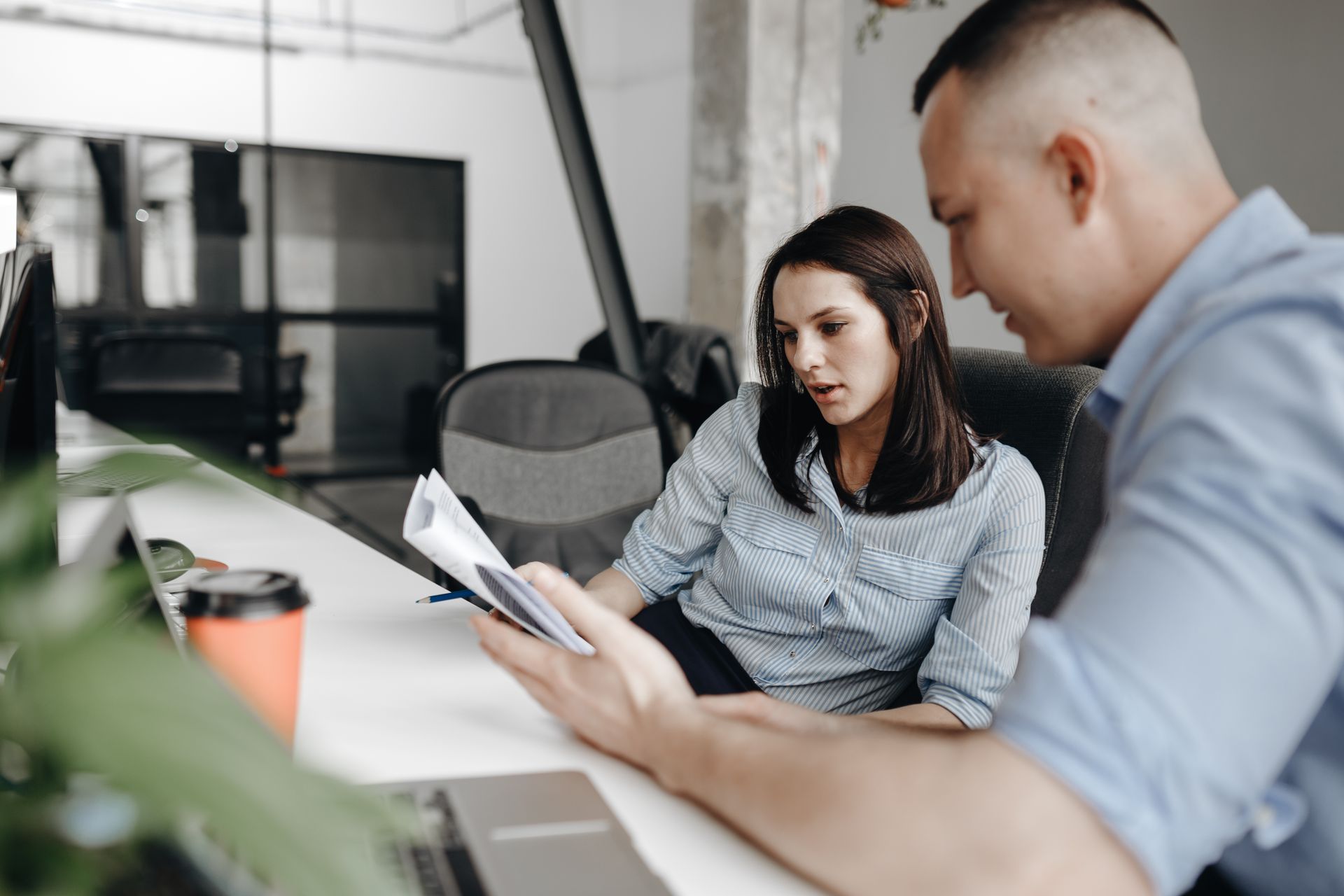 Woman and man in an office review documents; focused expressions.