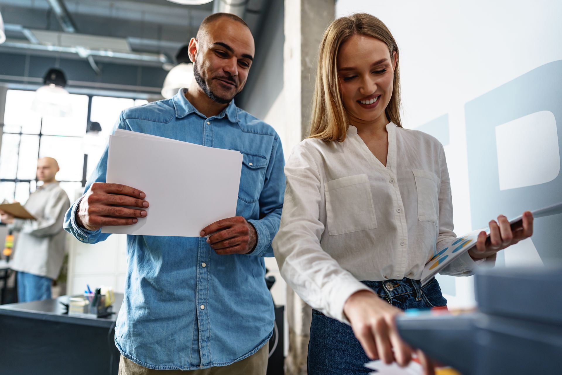 Man shaking hands with another person at a table, near a laptop and coffee cups.