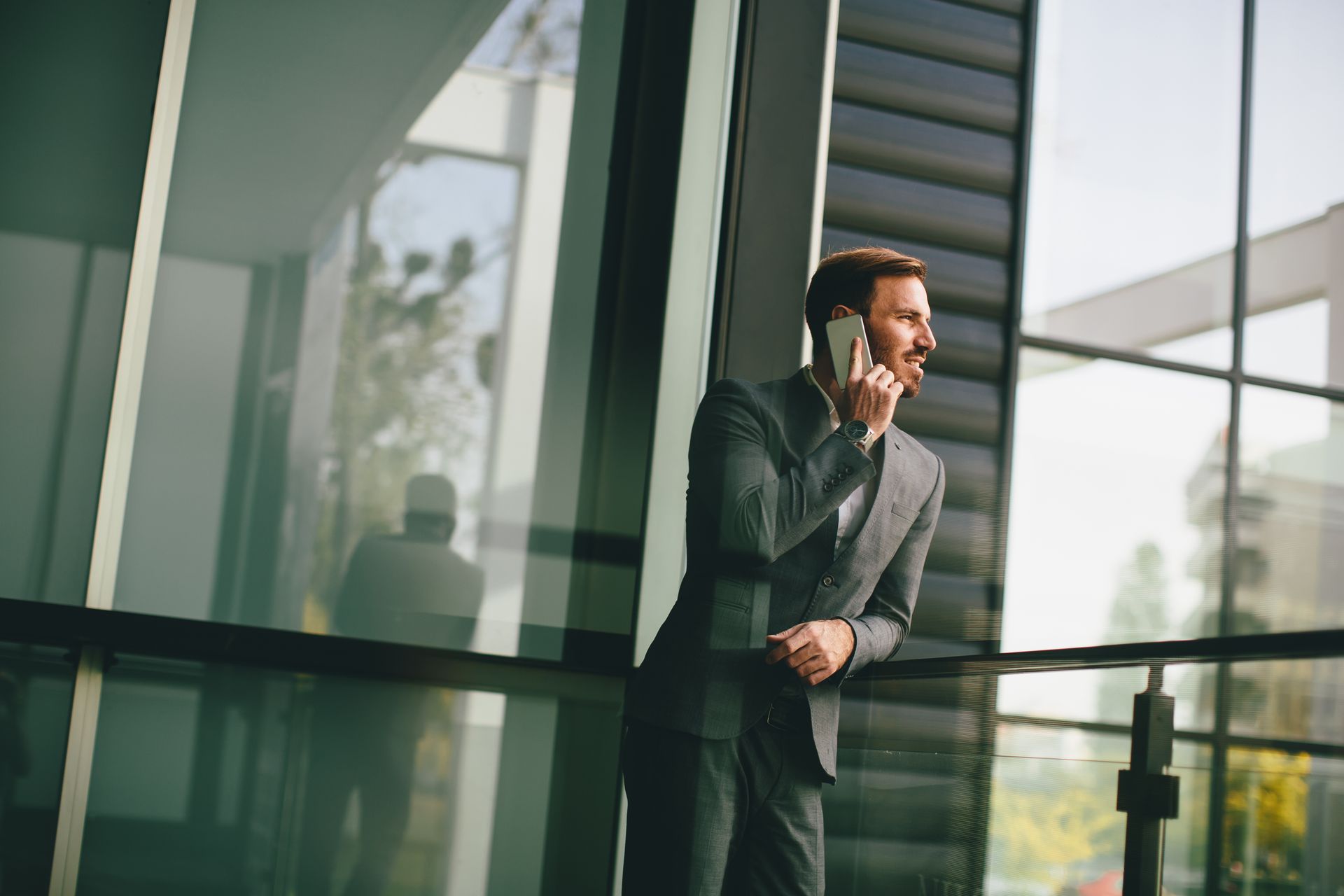 Man in suit talking on phone outside modern building.