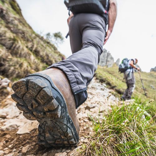 A person wearing hiking boots is walking down a rocky path.