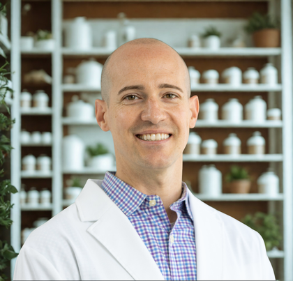 A bald man in a plaid shirt is smiling for the camera.