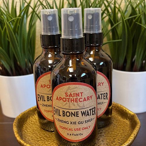 Four bottles of saint apothecary evil bone water are sitting on a gold tray.