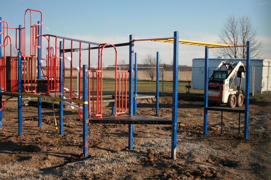 a red and blue playground with a bobcat in the background