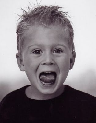 a young boy is sticking his tongue out in a black and white photo .