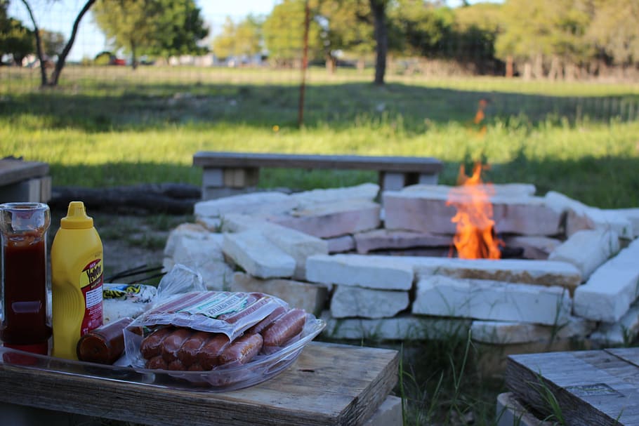 An outdoor fire pit with a blazing fire, perfect for grilling hotdogs and sausages over an open flame.