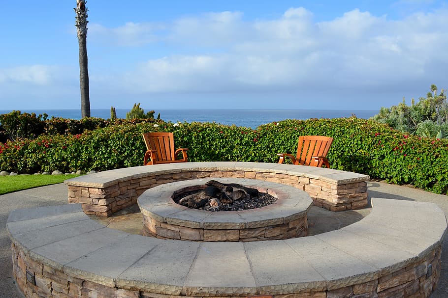 An empty fire pit waiting to be ignited, surrounded by rustic stones and cozy chairs.