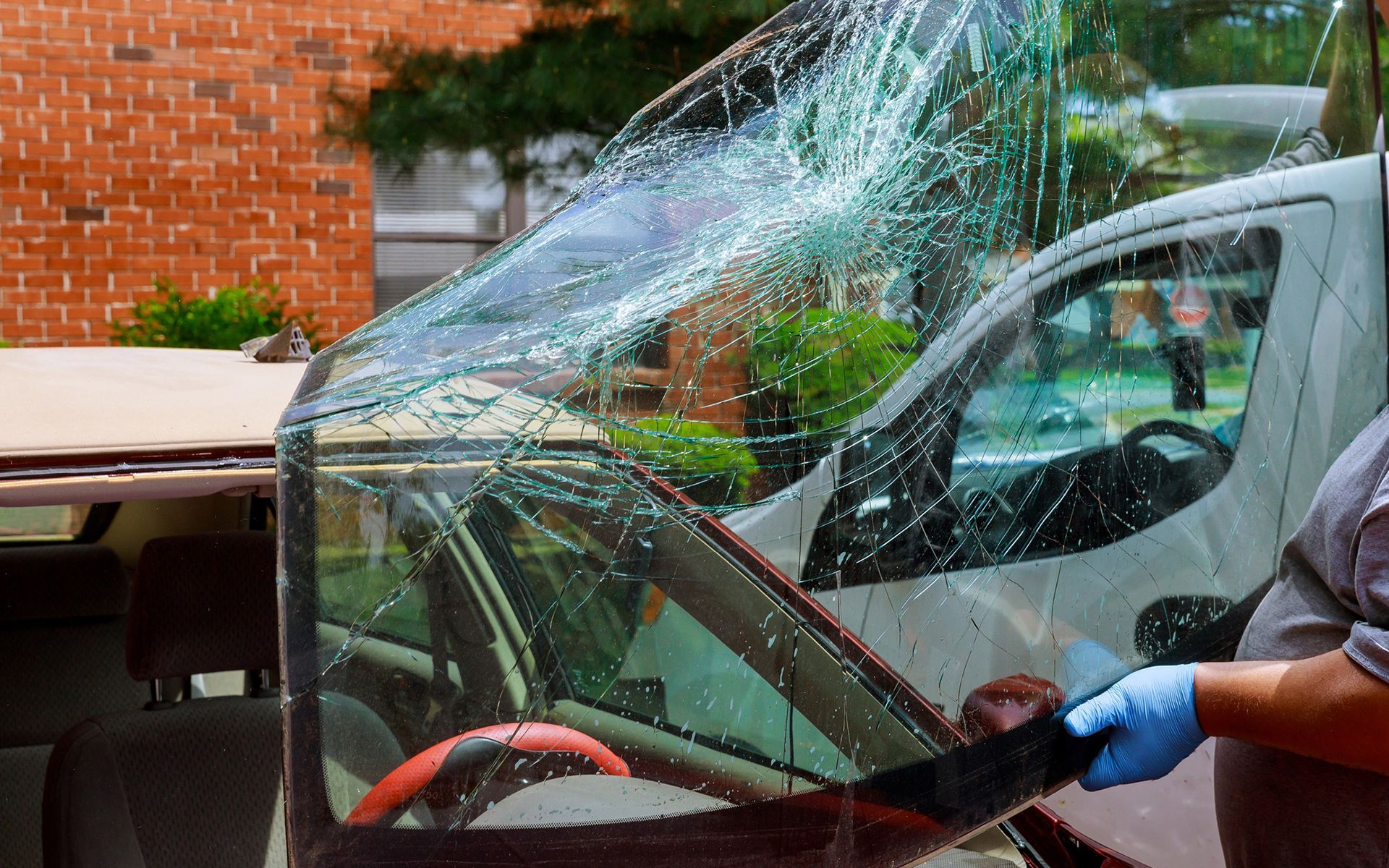 A man is cleaning a broken windshield of a car.