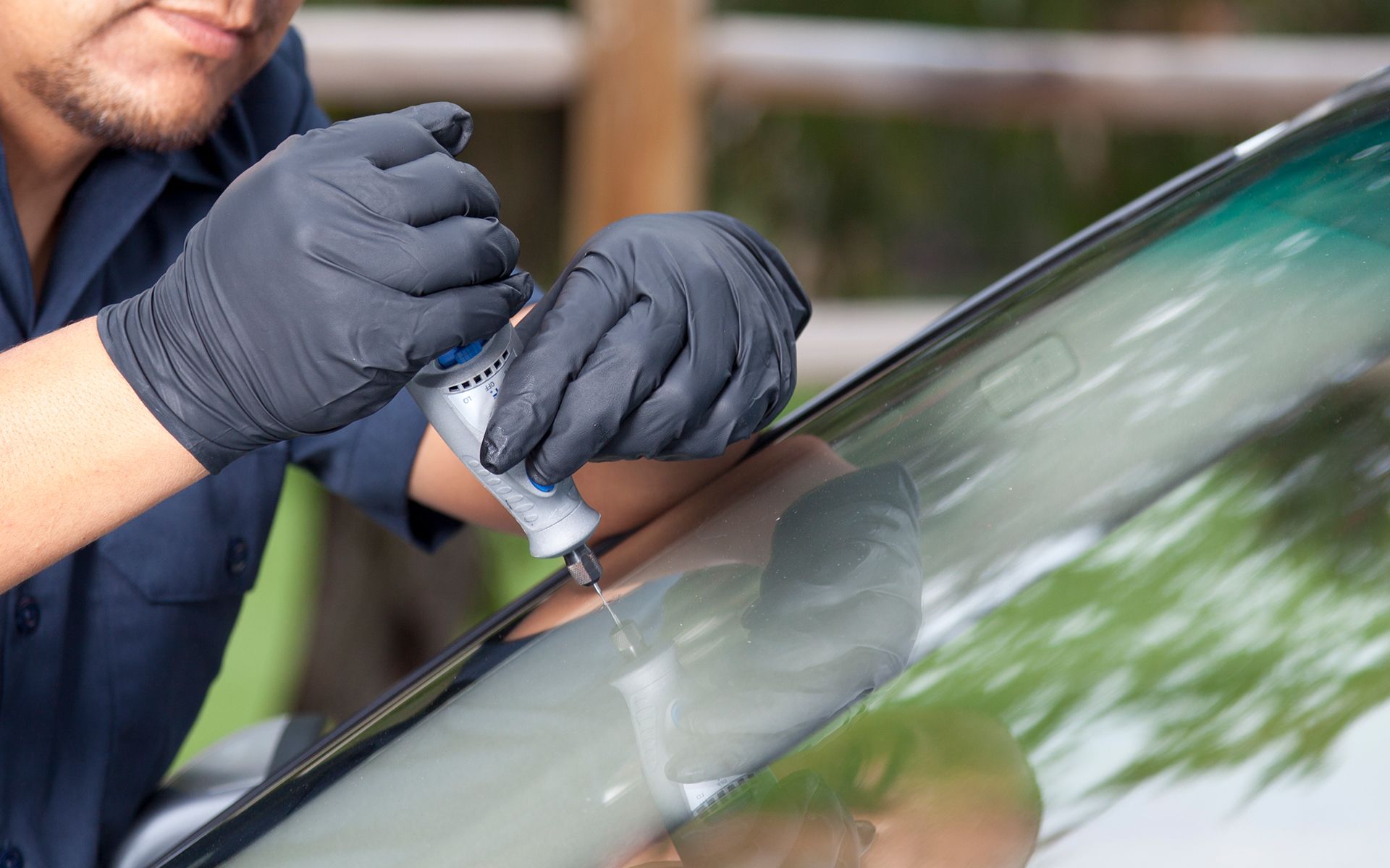 A man is repairing a windshield on a car.