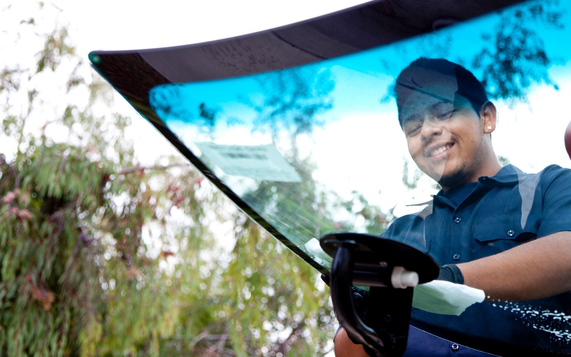 A man is fixing a windshield on a car in a garage.