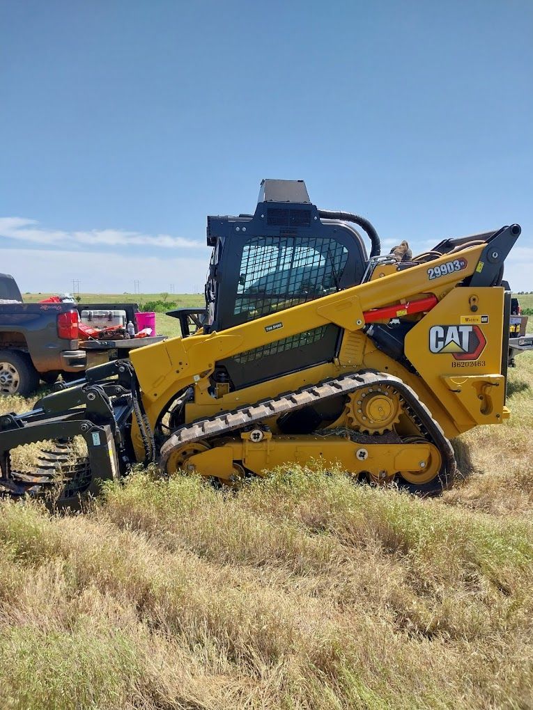 A yellow cat skid steer is parked in a field.