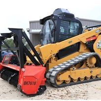 A bulldozer with a brush attached to it is parked in front of a building.