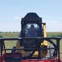 A man is driving a bulldozer in a field.