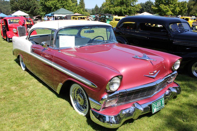 A red and white car is parked in the grass at a car show.