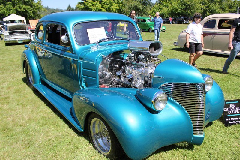 A blue car with the hood open is on display at a car show