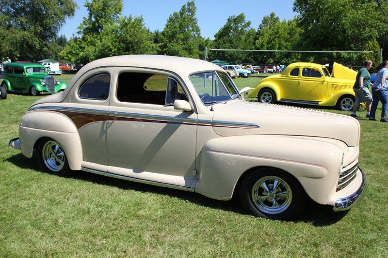 A white car is parked in the grass at a car show