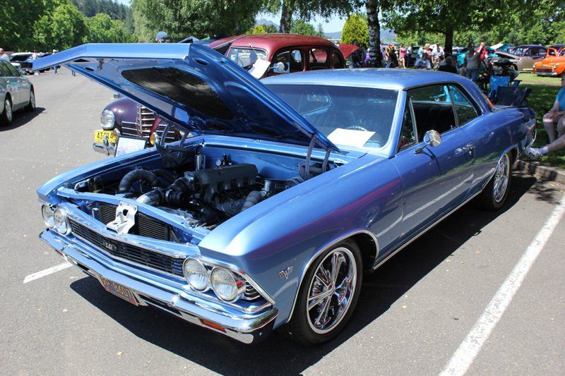 A blue car with the hood up is parked in a parking lot