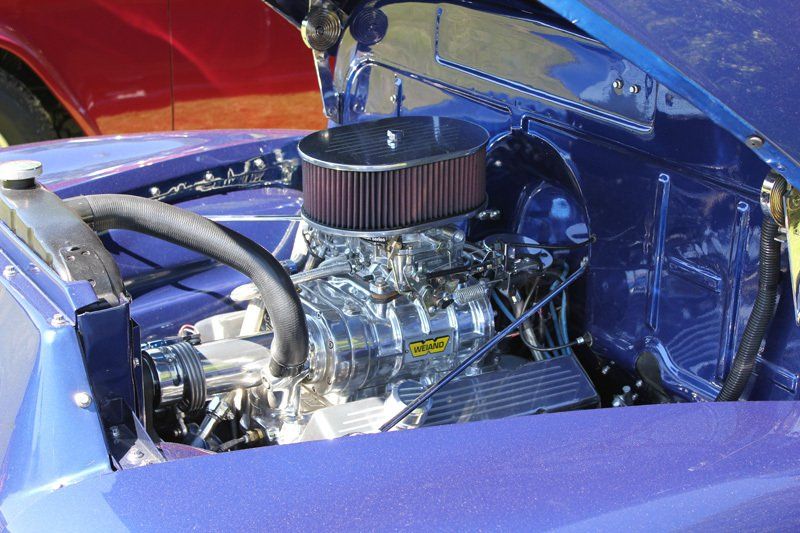A close up of a purple car engine with the hood open