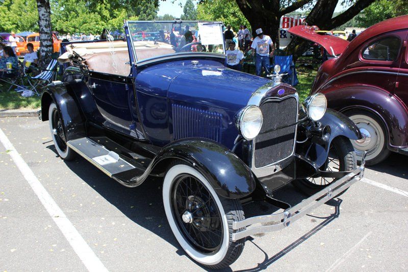 An old blue car is parked in a parking lot