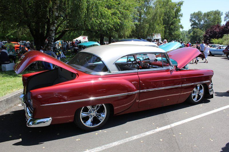 A red car with the hood up is parked in a parking lot