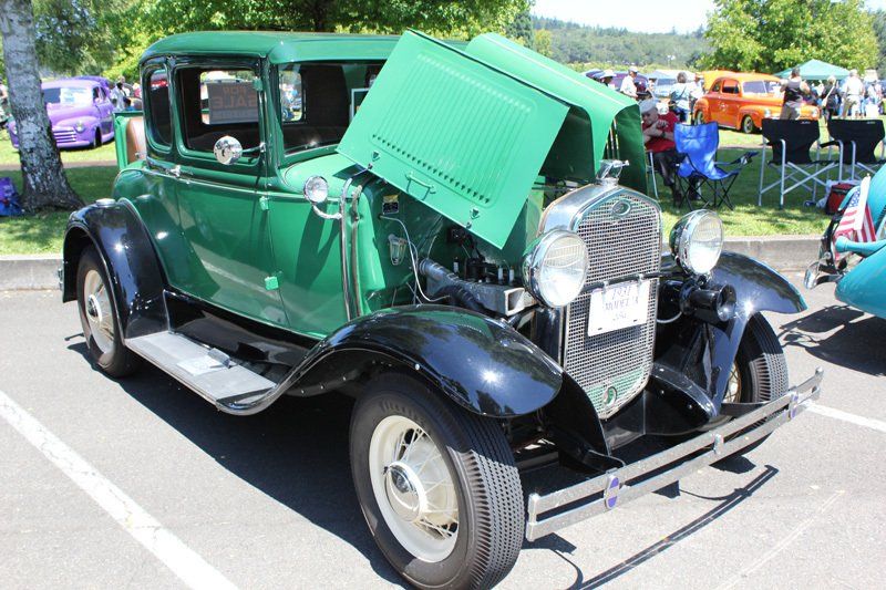 A green car with the hood up is parked in a parking lot