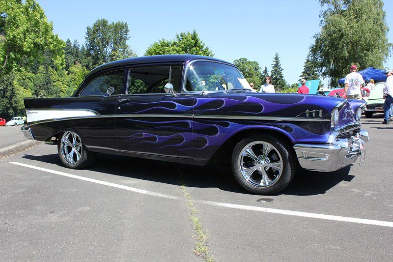 A purple car with flames painted on it is parked in a parking lot