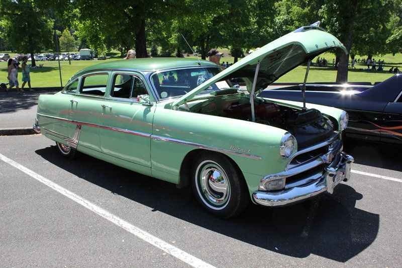 A green car with the hood up is parked in a parking lot