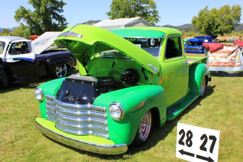 A green truck is parked next to a sign that says 28 27