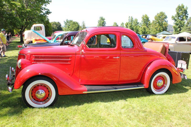 A red car with white tires is parked in the grass