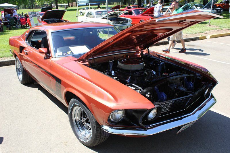 A red mustang with the hood up is parked in a parking lot