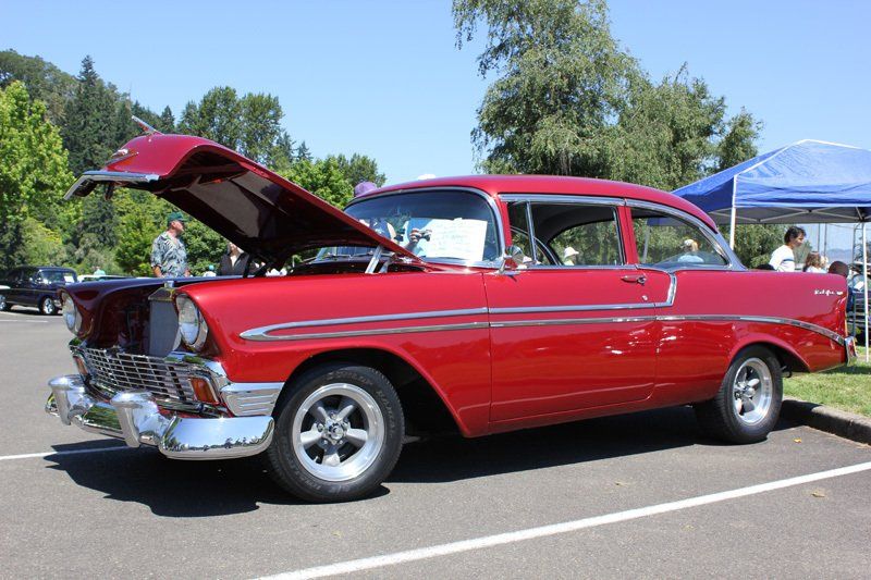 A red car with the hood up is parked in a parking lot