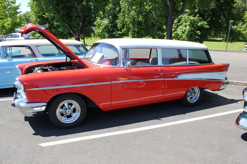 A red and white car with the hood up is parked in a parking lot