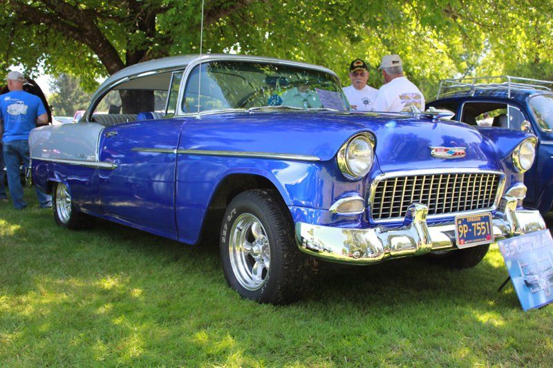 A blue and white car is parked in the grass.