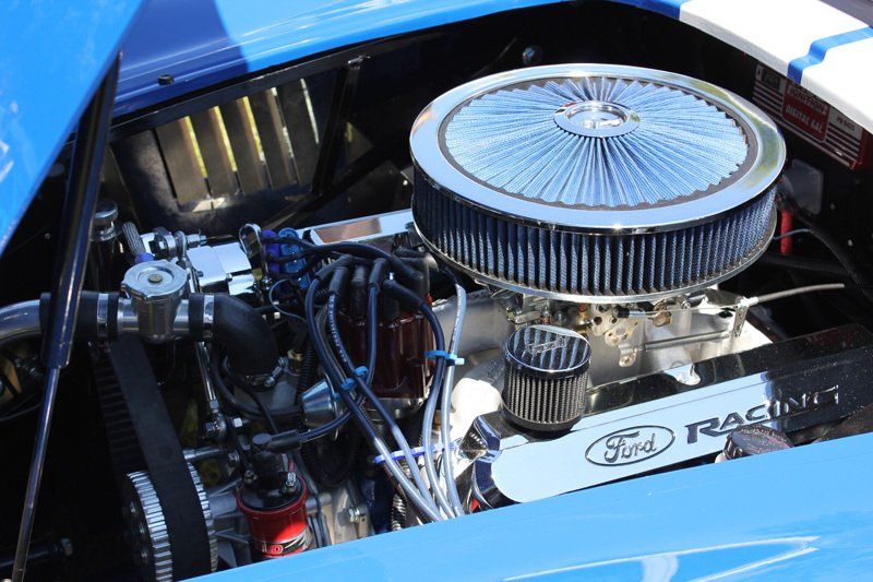 A close up of a blue car engine with the hood open