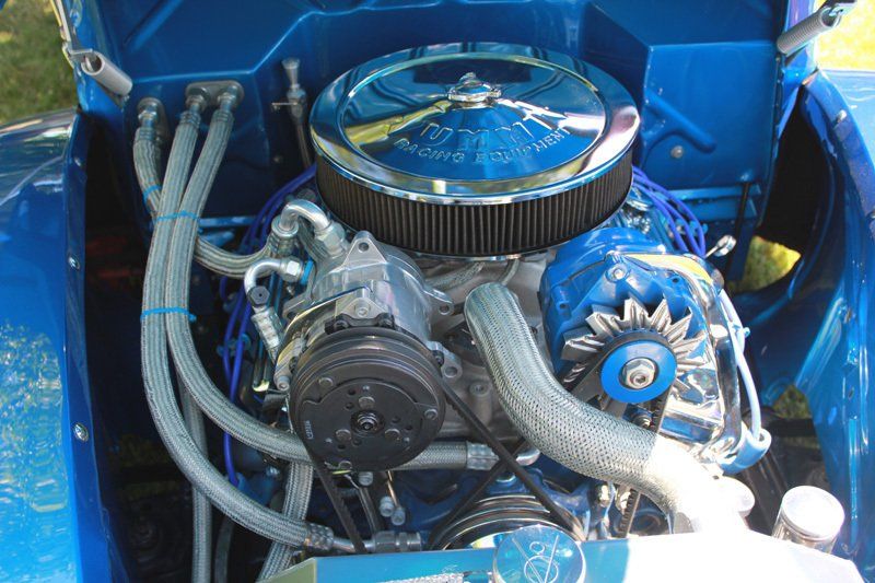 A close up of a blue car engine with a clock on it