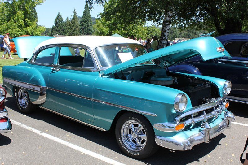 A blue and white car with the hood up is parked in a parking lot