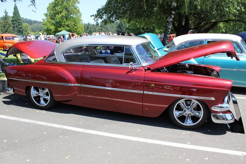 A red car with the hood up is parked in a parking lot