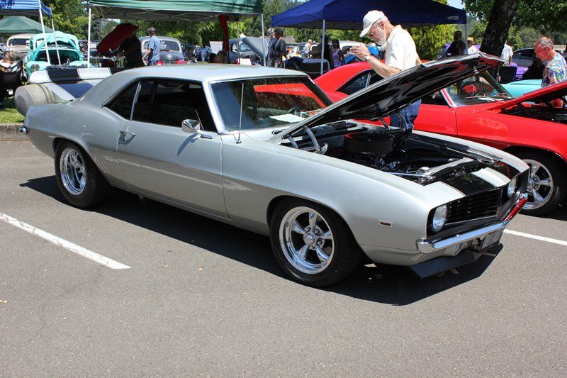 A man is looking under the hood of a silver car