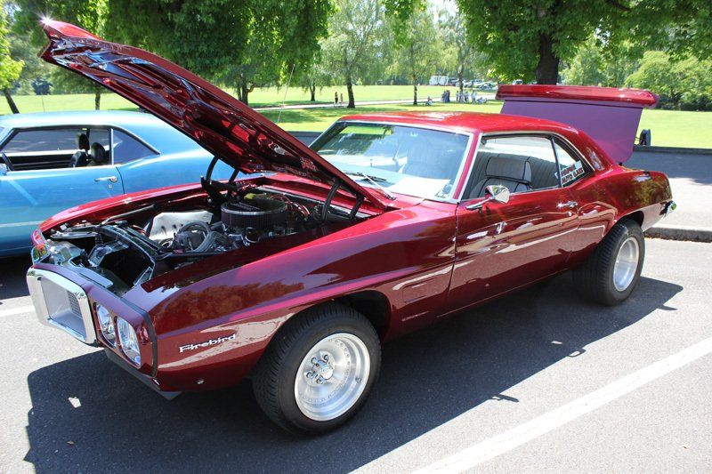 A red car with the hood up is parked in a parking lot
